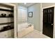 This is a bathroom with a soaking tub, built-in shelves and a dark-colored door at 4412 Thistlehill Ct, Raleigh, NC 27616
