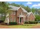 Two-story brick home featuring lush landscaping, a front entrance, and mature trees at 4412 Thistlehill Ct, Raleigh, NC 27616