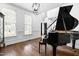 Bright living room featuring a grand piano, natural light, and hardwood floors at 4412 Thistlehill Ct, Raleigh, NC 27616