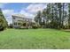 Expansive backyard featuring a lush lawn, mature trees, and a covered patio for outdoor entertaining at 5112 Highbury Grove Ln, Fuquay Varina, NC 27526