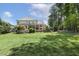 Expansive backyard featuring a lush lawn, mature trees, and a covered patio for outdoor entertaining at 5112 Highbury Grove Ln, Fuquay Varina, NC 27526