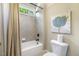 Bright bathroom with a shower-tub combo, decorative art, and tiled walls at 5112 Highbury Grove Ln, Fuquay Varina, NC 27526