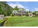 Beautifully landscaped home with a lush lawn, mature trees, and an elegant brick facade with black shutters at 5112 Highbury Grove Ln, Fuquay Varina, NC 27526