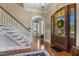 Bright foyer featuring hardwood floors, a staircase, arched doorway, and a view of the front yard at 5112 Highbury Grove Ln, Fuquay Varina, NC 27526