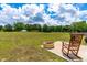 Backyard showcasing a fire pit, rocking chair, lush green grass, and distant trees at 60 Waterwheel Dr, Selma, NC 27576