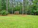 A spacious green yard features tall trees and an outbuilding, perfect for enjoying the outdoors at 635 Buckroe Dr, Sanford, NC 27330
