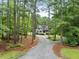 A gray two-story home is approached by a gravel driveway through a forest at 635 Buckroe Dr, Sanford, NC 27330