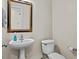 A powder room with a pedestal sink, decorative mirror, and toilet at 635 Buckroe Dr, Sanford, NC 27330