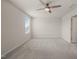 An empty bedroom with a ceiling fan, a large window, and neutral carpeting at 6618 Perry Creek Rd, Raleigh, NC 27616