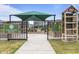 Fenced community garden with picnic tables, raised garden beds, and shaded seating at 6618 Perry Creek Rd, Raleigh, NC 27616