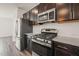 Modern kitchen with stainless steel appliances, dark cabinets, granite countertops, and a gas range stove at 6618 Perry Creek Rd, Raleigh, NC 27616