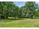 Backyard view with green grass and tall trees at 8509 Ashwood Dr, Raleigh, NC 27603