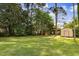 Spacious backyard with lush green grass, mature trees, and a convenient storage shed at 905 S 1St St, Smithfield, NC 27577