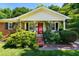 Inviting front porch and red door on this home with lush landscaping and charming curb appeal at 1008 Mockingbird Dr, Raleigh, NC 27615