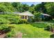 Charming home with a lush green lawn, mature trees, and a welcoming front porch with a bright red door at 1008 Mockingbird Dr, Raleigh, NC 27615