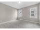 An empty bedroom with gray carpet and natural light from two windows at 1029 Whitehall Cir, Durham, NC 27713