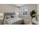 A bedroom featuring two windows with a grey bed and decorative pillows, and a marble table with flowers at 105 Walehurst Ridge Dr, Angier, NC 27501