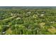 Wide aerial perspective revealing the property amidst a mix of wooded areas and open fields in a rural location at 1052 Hughes Trl, Elon, NC 27244