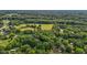 Expansive aerial view capturing a rural landscape with trees, fields, and scattered houses, showcasing the property's surroundings at 1052 Hughes Trl, Elon, NC 27244