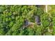 Aerial view of a house nestled in a lush forest with outbuildings and a gravel driveway at 1052 Hughes Trl, Elon, NC 27244