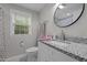 Modern bathroom with a granite countertop, white cabinets, and a round mirror at 1052 Hughes Trl, Elon, NC 27244