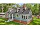View of the home's exterior showcasing dormer windows, an enclosed sunroom, brick foundation, and a welcoming entrance at 1052 Hughes Trl, Elon, NC 27244