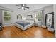 Comfortable main bedroom features a ceiling fan, hardwood floors, and large windows at 1052 Hughes Trl, Elon, NC 27244