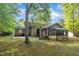 A tree-filled backyard is the backdrop to the house and sunroom at 1115 Chestnut Dr, Smithfield, NC 27577