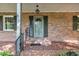 Charming front porch with brick flooring, painted white support columns and dark shutters at 1115 Chestnut Dr, Smithfield, NC 27577