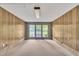Spacious living room featuring wood-paneled walls and light-filled glass doors at 1115 Chestnut Dr, Smithfield, NC 27577