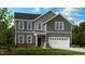 Charming two-story home with gray siding, a white two car garage, and a manicured front yard at 1128 Sun Springs Rd, Wake Forest, NC 27587