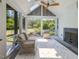 Comfortable sunroom with white wood paneling, ceiling fan, fireplace, and views of the landscaped backyard at 115 Founders Ridge Dr, Chapel Hill, NC 27517