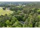 Scenic aerial view of a home nestled among dense trees with a neighborhood in the distance at 118 Cavendish Ct, Hillsborough, NC 27278