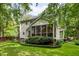 Back exterior highlighting a screened porch, manicured landscaping, and lush greenery at 118 Cavendish Ct, Hillsborough, NC 27278