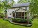 Rear exterior showcasing a screened-in porch, a manicured lawn, and landscaped garden at 118 Cavendish Ct, Hillsborough, NC 27278