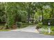 View of the home's facade and driveway, showcasing its serene setting among mature trees and landscaping at 118 Cavendish Ct, Hillsborough, NC 27278