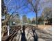 A tennis court is visible through a fence amidst trees and landscaping on a sunny day at 119 Brookberry Cir, Chapel Hill, NC 27517
