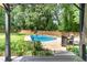 Backyard with inground swimming pool, wooden fence, and mature trees surrounded by green lawn at 1209 Lanark Ct, Cary, NC 27511