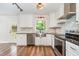 A stylish kitchen featuring white cabinets, stainless steel appliances, granite countertops, and hardwood floors at 1209 Lanark Ct, Cary, NC 27511