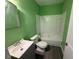 A green bathroom features a vanity with a white sink and a tub and shower combo at 1525 Hargrove St, Rocky Mount, NC 27801