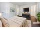 A staged bedroom showcasing a bed with white linens, a dresser, and modern decor with hard wood floors at 216 E Hinton St, Clayton, NC 27520