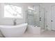 Luxurious bathroom featuring a soaking tub and glass-enclosed shower with herringbone tile accents at 25 Alex Farm Ct, Zebulon, NC 27597