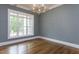 A bright living room features hardwood floors, a modern chandelier, and a large window for natural light at 25 Alex Farm Ct, Zebulon, NC 27597
