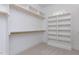 Organized walk-in closet with white shelving units, wood rods, and neutral carpet at 25 Alex Farm Ct, Zebulon, NC 27597