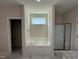 Bathroom featuring a soaking tub with shower, a window and glass shower at 322 Busterfield Ct, Benson, NC 27504