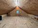 Spacious attic features wood-paneled walls and floors, a small window, and a modern light fixture at 358 Pool Rock Shores Ln, Henderson, NC 27537