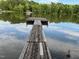 Lake view featuring a weathered wooden pier stretching into the water, reflecting the sky and trees at 358 Pool Rock Shores Ln, Henderson, NC 27537