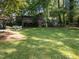Picturesque backyard with green grass, large trees, covered seating, and a rustic wooden playhouse at 3620 Arrowwood Dr, Raleigh, NC 27604