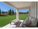 Covered patio with cozy seating overlooks a lush green lawn and landscaping at 408 Grand Silo Rd, Garner, NC 27603