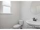 Well-lit half bathroom featuring a modern toilet and a stylish pedestal sink with sleek fixtures, and window at 412 Longleaf Glen Lane, Zebulon, NC 27597